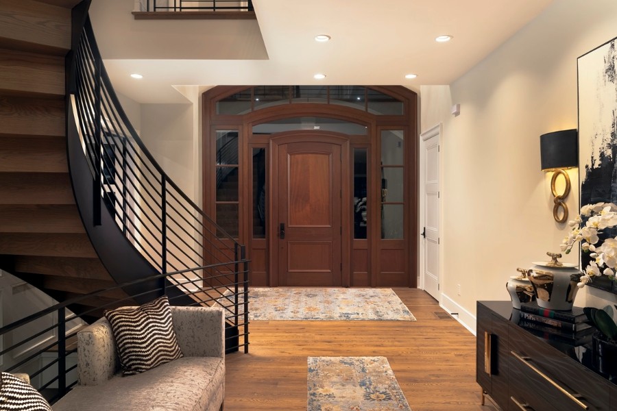 A hallway featuring a staircase and a couch illuminated by Lutron lighting.