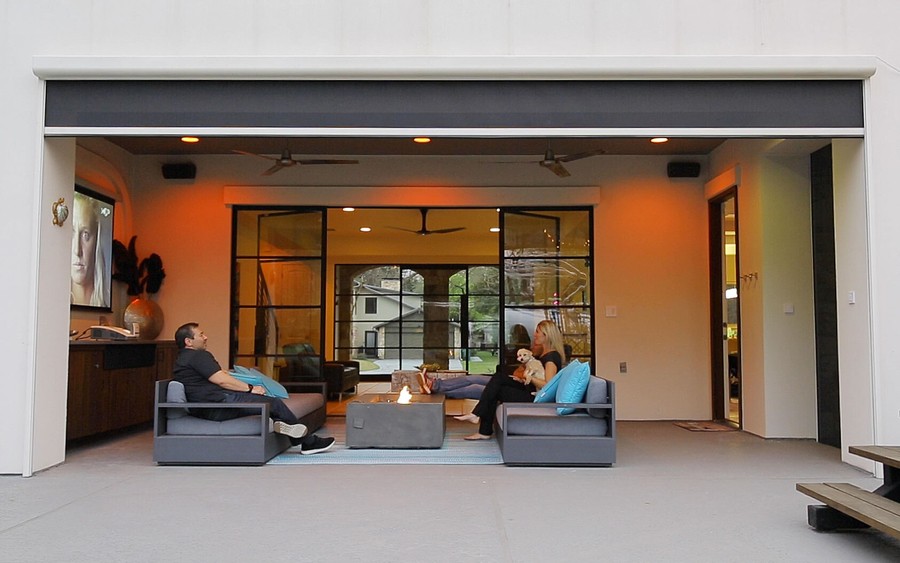 People sitting in a home entertainment space with a raised Screen Innovations shade over the opening.