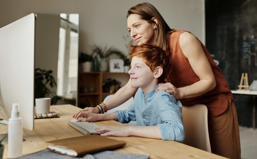 A mother helping her son access online resources from a strong network installation and connection.