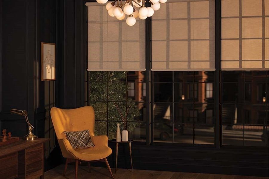 A beautiful sitting room at night, large windows with motorized shades overlooking a patio.